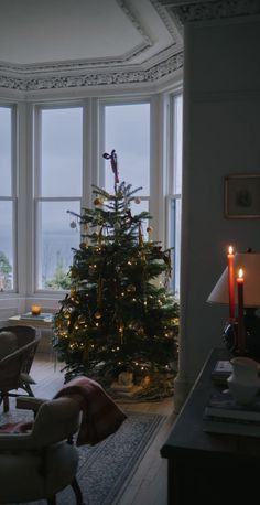 a living room with a christmas tree in the corner and two candles on the table