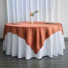 an orange and white table cloth on top of a round table with two plates in front of it