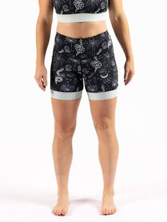 a woman in black and white patterned shorts with her hands on her hips, looking at the camera