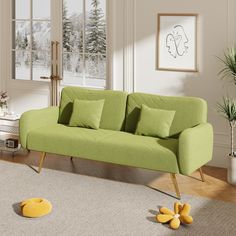 a green couch sitting on top of a wooden floor next to a potted plant