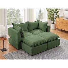 a green couch sitting on top of a wooden floor next to a table and lamp