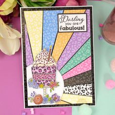 a card with a birthday cake on it and flowers in the background, next to some confetti