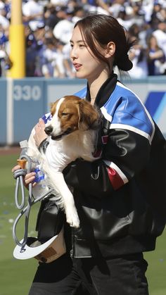 a woman holding a dog in her arms at a baseball game while people watch from the stands