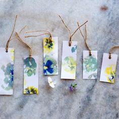 four tags with flowers painted on them hanging from twine