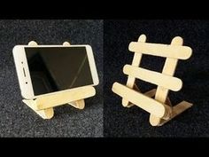 two small wooden toys sitting next to each other on the floor and one is holding a tablet