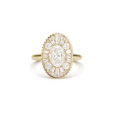 a yellow gold ring with an oval shaped diamond surrounded by smaller round diamonds on the band