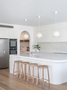 a kitchen with an island and three stools next to the refrigerator freezer in it