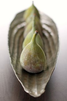 two figurines sitting on top of a leaf shaped object with water running down it