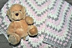 a teddy bear sitting on top of a crocheted blanket next to a wooden floor