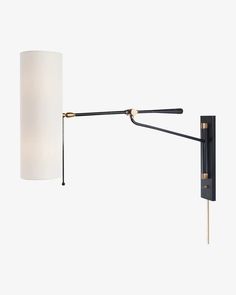 a black and gold wall light with a white shade on the arm, against a white background