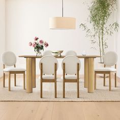 a dining room table with four chairs and a vase of flowers on the table next to it