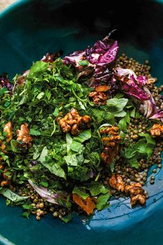 a blue bowl filled with greens and lentils