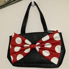 This Disney Parks Handbag Features The Iconic Minnie Mouse Character With A Stylish Oversized Bow Design. The Bag Is Perfect For Carrying Everyday Essentials And Is Made Of Durable Materials To Withstand Daily Use. The Black, Red, And White Color Scheme Matches Any Outfit And The Medium Size Allows For Easy Storage While Still Being Spacious Enough For All Your Belongings. The Bag Is A Great Addition To Any Disneyana Collection And Is Sure To Be A Hit With Any Disney Fan. Light Scuff On Dot On B Black Minnie Mouse Bag For Disney Trips, Disney Satchel Bag For Everyday Use, Trendy Black Minnie Mouse Bag, Black Minnie Mouse Bag For Everyday Use, Cute Minnie Mouse Travel Bag, Trendy Minnie Mouse School Bag, Red Disney Bag With Zipper Closure, Red Minnie Mouse Travel Bag, Disney Style Minnie Mouse Bag For Disney Trips