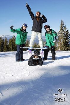 three snowboarders are posing for a photo on the top of a snowy hill