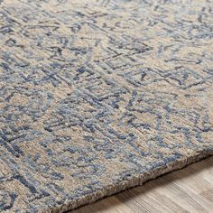 an area rug with blue and beige designs on the top, along with wood flooring