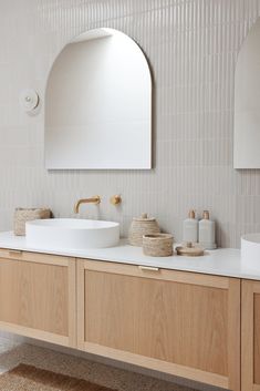 a white sink sitting under a mirror next to a wooden cabinet and wall mounted faucet