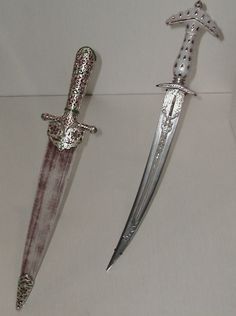 two swords are sitting next to each other on a white tablecloth covered countertop