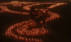 a woman kneeling down in front of a circle of candles that are shaped like hearts