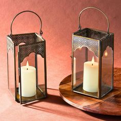 two lit candles sitting on top of a wooden table