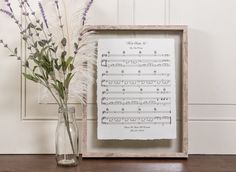 a vase with flowers and sheet music in it next to a framed musical score print