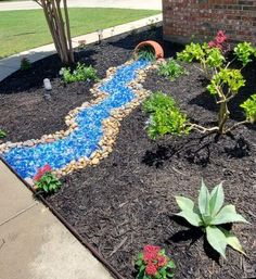 there is a small garden with flowers and rocks in the front yard, next to a brick building