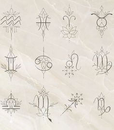 an assortment of zodiac symbols on a white marble background with black lines in the middle