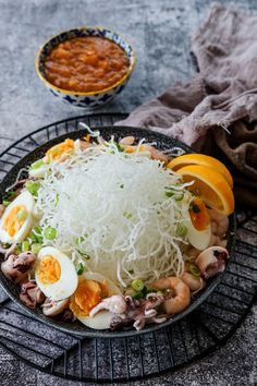 a plate with noodles, eggs and vegetables on it next to a bowl of beans