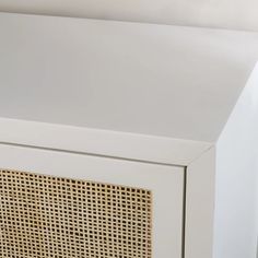 a white cabinet with wicker on the front