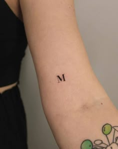 a woman's arm with the letter m tattooed on it