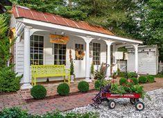 a small white house with a yellow bench in the front yard and red brick walkway leading up to it