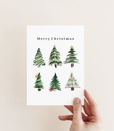 someone holding up a card with christmas trees on it