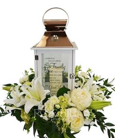 a lantern filled with white flowers and greenery next to a candle holder that reads, the family