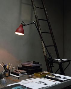 a red lamp sitting on top of a wooden table next to a book and other items