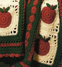 a crocheted blanket with an apple on the front and back, sitting on top of a chair