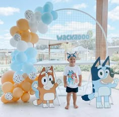 a little boy standing in front of a bunch of balloons with cartoon characters on them