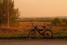 a bike is parked on the side of the road in front of some grass and trees