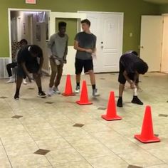 several young men standing around orange cones on the floor