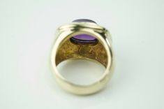 Beautiful amethyst cocktail ring! The stunning deep purple bezeled cabochon stone measures approx. 8.69mm x10.55mm. The stone sits in a tired brightly polished 14k yellow gold rectangular setting. The face of the ring measures 17.23mm from North to South and 20.10mm from east to west and sits approx. 10.5mm high off the finger. the shank in tapers from 11.6mm at the side of the face to 5.3mm at the finger. The ring currently is sized at a 6.5, but can easily be resized by a qualified jeweler. Th Luxury Purple Amethyst Cabochon Ring, Luxury Purple Cabochon Amethyst Ring, Luxury Purple Amethyst Oval Cabochon Ring, Formal Purple Cabochon Gemstones, Formal Oval Cabochon Amethyst Ring, Formal Purple Cabochon Amethyst Ring, Formal Purple Cabochon Ring, Classic Amethyst Cabochon Ring For Formal Occasions, Classic Amethyst Oval Cabochon Ring