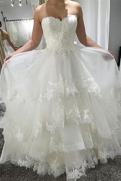 a woman in a white wedding dress looking at herself in the mirror