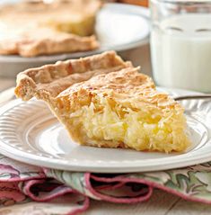 a piece of pie sitting on top of a white plate next to a glass of milk