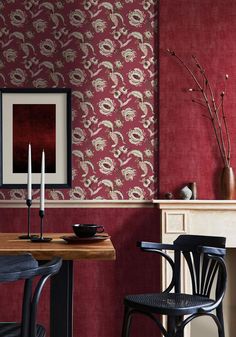 two chairs and a table in front of a red wall