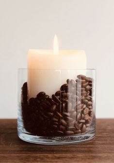 a lit candle is surrounded by coffee beans