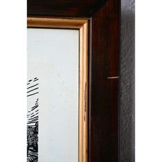 an old wooden frame with a black and white drawing on the wall next to it