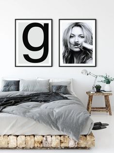 two black and white pictures hang above a bed in a room with grey linens