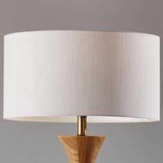 a wooden table lamp with a white lampshade on the base and a beige shade