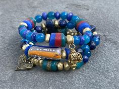 Blues hues; Lapis; Blue Jade; African Krobo beads,; Asanthi glass beads; Brass; wood; Stacking bracelet; Boho; Tribal; Luck; Heart bracelet Price is for one bracelet. Purchase all three for a complete look Style 1: This beautiful boho  bracelet is made of Lapis, Agate, African Krobo beads, and Brass beads. Brass heart charm accentuates the bracelet Style 2: This beautiful boho  bracelet is made of Lapis, Agate, African Krobo beads, Ashanti glass beads and Brass beads. Style 3:This beautiful boho  bracelet is made of Lapis, Jade, Agate, African Krobo beads, Ashanti glass beads and Brass beads. Elephant charm accentuates this bracelet. This bracelet fits wrist size 5 and half inches to 6 and half inches. Please convo with me if you need a different size. Please Note: I do my best to capture Blue Bohemian Beaded Bracelets With Wooden Beads, Bohemian Blue Beaded Bracelets With Wooden Beads, Bohemian Blue Bracelets With Wooden Beads, Blue Wooden Beaded Bracelets As Gift, Unique Blue Beaded Bracelets For Festival, Blue Wooden Beads For Festival, Artisan Blue Bracelets With Spacer Beads, Blue Wooden Beads Bracelet, Blue Heart Beads Jewelry For Festivals