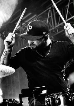 a man with a baseball cap is playing drums