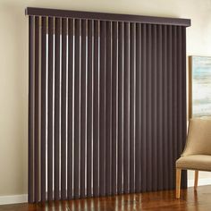 a chair sitting in front of a window with brown vertical blinds on the windowsill