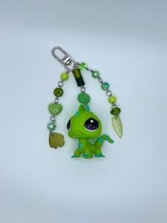 a keychain with a little green creature on it's side and charms attached to it