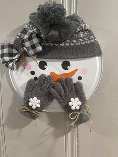 a snowman door hanger with gloves on it